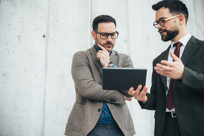Zwei Geschäftsmänner mit Tablet in Diskussion