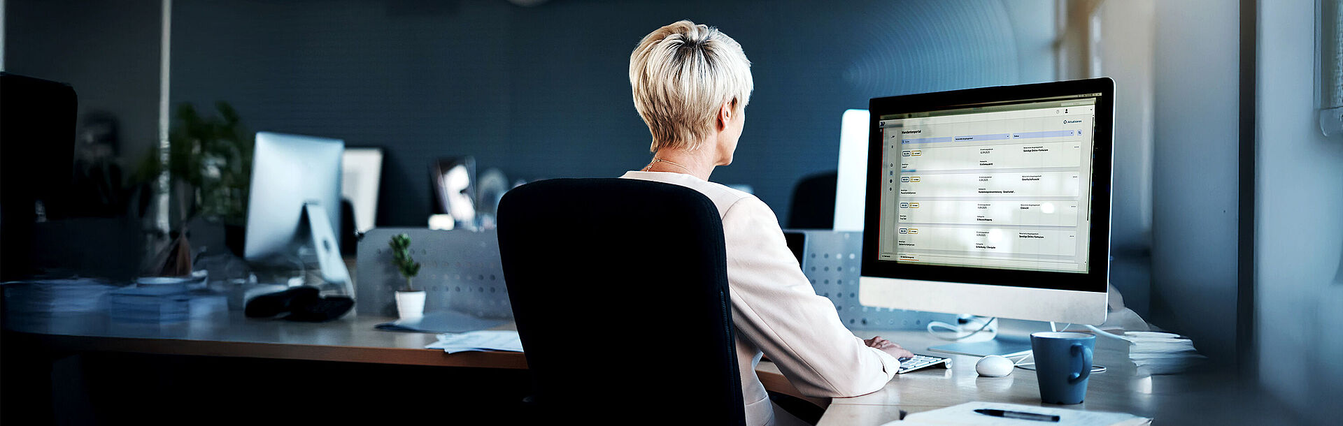 Frau sitzt am Monitor in einem Büro; Bild zum Start des Mandantenportals der Bundesnotarkammer