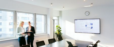 Zwei leicht verschwommene Frauen unterhalten sich in einem Büroraum