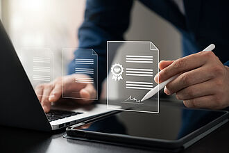 Symbolbild für elektronische Beurkundung: Geschäftsmann unterzeichnet am Laptop Vertrag